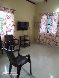 a living room with two chairs and a flat screen tv at GARDEN VILLA (Home Stay) in Dharmastala