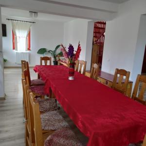a dining room with a red table and chairs at Pensiunea Agroturistica Alexandra in Smida