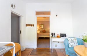 a living room with a blue couch and a bedroom at Bridport Garden Suite in Bridport