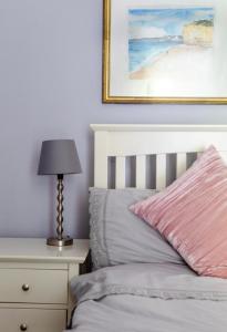 a bed with a pink pillow and a lamp on a nightstand at Bridport Garden Suite in Bridport