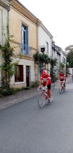 dos personas montando sus bicicletas por una calle en L'arbrissel en Fontevraud-l'Abbaye