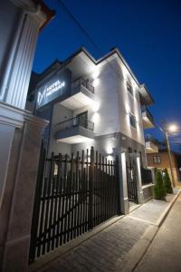 a white building with a gate in front of it at Mergan Hotel in Korçë