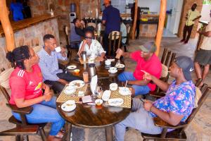 un grupo de personas sentadas en mesas en un restaurante en Akagera Transit Lodge en Akagera