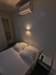 a bedroom with a white bed with a air conditioner on the wall at BeB Hotel in Macapá