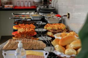 um buffet cheio de diferentes tipos de alimentos em pratos em Pousada Catavento em Pipa