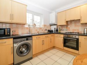 a kitchen with wooden cabinets and a washer and dryer at Siena Cottage, 41a Kents Lane in Torquay