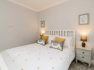 a white bedroom with a large white bed with pillows at Siena Cottage, 41a Kents Lane in Torquay