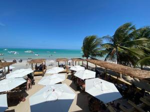 a beach with white umbrellas and the ocean at Barra lounge in Maragogi