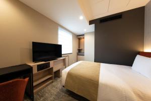 a hotel room with a bed and a flat screen tv at Almont Hotel Nippori in Tokyo