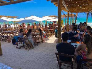 a group of people sitting at tables on the beach at Barra lounge in Maragogi