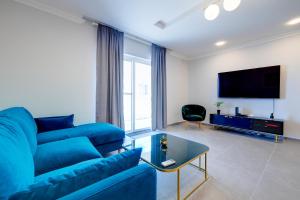 Una sala de estar con un sofá azul y un televisor de pantalla plana. en Art Deco Luxury Apartment, Central Location, en Sliema