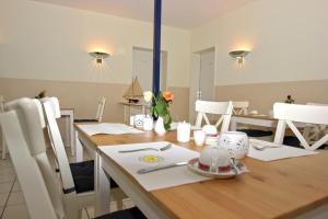 una sala da pranzo con tavolo in legno e sedie bianche di F-1010 Strandhaus Mönchgut Bed&Breakfast DZ 33 Balkon, strandnah, inkl Frühstück a Lobbe