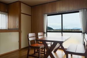 una sala da pranzo con tavolo, sedie e finestra di とまばりゲストハウス a Sanuki