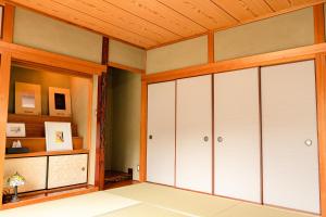 Cette chambre est dotée de portes blanches et d'un plafond en bois. dans l'établissement とまばりゲストハウス, à Sanuki