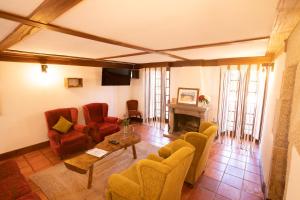 uma sala de estar com cadeiras, uma mesa e uma lareira em Casa da Cerca em Sortelha