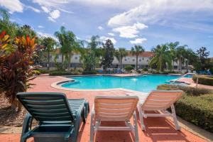 drei Stühle neben einem Swimmingpool in der Unterkunft Magical Fiesta Key Townhouse in Kissimmee