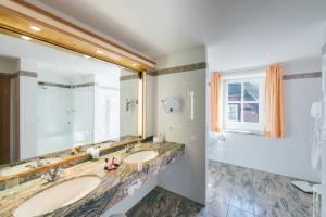 baño con 2 lavabos y espejo grande en Hotel Landhaus Höpen, en Schneverdingen