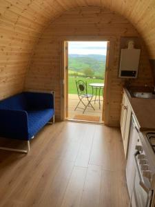 Habitación con sofá azul y mesa en una cabaña en Woodpecker Pod with views, en Lampeter