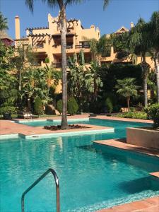 uma piscina com um hotel ao fundo em El Real De El Campanario em Estepona
