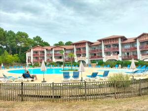 a pool at a resort with chairs and umbrellas at Appart-dans Résidence de vacances au coeur du Golf-Le domaine de Gascogne in Biscarrosse