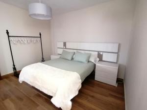 a bedroom with a white bed with a white blanket at A Casa dos Retales in Cangas de Morrazo