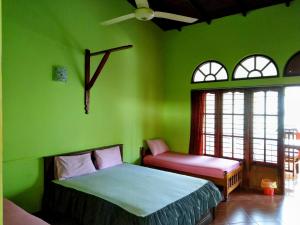 Dormitorio verde con cama y ventana en Kandyan Feel Free Homestay en Kandy