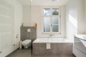 a bathroom with a tub and a toilet and a window at De Hoogmolen - 3 mins from the city centre in Bruges +29 photos
