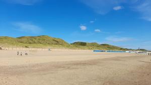 two people walking on a beach with mountains in the background at Vakantiewoning aan duinen en zee in Dishoek in Dishoek