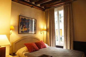a bedroom with a bed with red pillows and a window at Hôtel du Cygne Paris in Paris