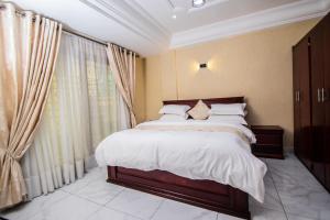 een slaapkamer met een bed met witte lakens en gordijnen bij Residence Le Bonheur - 2 Bed Apartment by Douala Mall/Airport in Douala