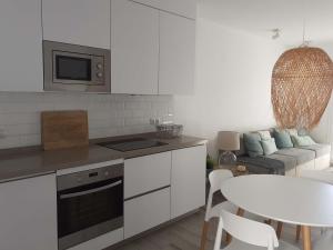 a white kitchen with a table and a couch at Precioso Apartamento a 20 metros del mar in Agua Amarga