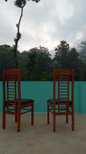 two wooden chairs sitting next to a green wall at Wayanad Snow Vibes in Vythiri