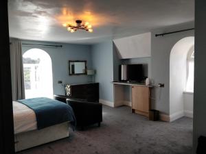 una camera da letto con un letto, una scrivania e una televisione di The Shirley a Torquay