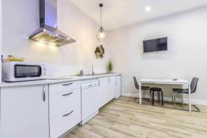 uma cozinha com armários brancos e uma mesa com um micro-ondas em Acogedor Apartamento entre Sol Gran Vía y Palacio em Madri