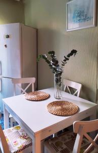 uma mesa branca com duas cadeiras e um vaso com flores em Kremlyovskaya Apartament em Vladimir