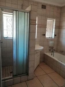 y baño con ducha, bañera y lavamanos. en NTUMBA VILLA, en Vereeniging