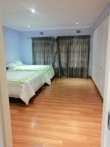 1 dormitorio con 2 camas y suelo de madera en NTUMBA VILLA, en Vereeniging