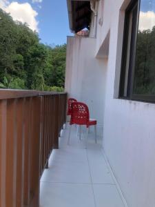 a red chair sitting on a balcony with a window at Dei Fiori Guaramiranga in Guaramiranga