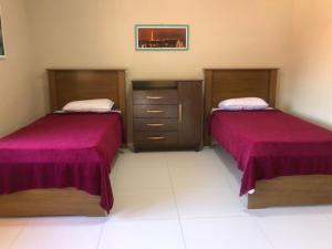 2 bedden in een kamer met paarse lakens bij Dei Fiori Guaramiranga in Guaramiranga