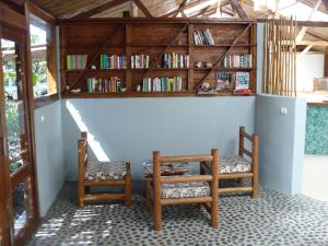 a room with two chairs and a table and bookshelves at Hotel Ecolodge Riake Resort & Villa in Sainte Marie