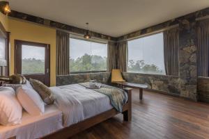 a bedroom with a bed and a desk and windows at Fort WindShire in Nuwara Eliya