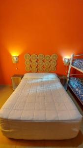 Cama grande en habitación con pared de color naranja en Casa en Cafayate en Cafayate