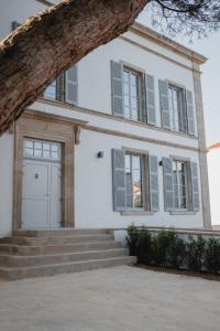 uma casa branca com janelas cinzentas e escadas em Hôtel-Restaurant Villa Métis em Les Herbiers