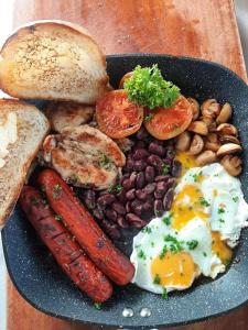 a plate of food with eggs sausage beans and bread at Fort WindShire in Nuwara Eliya