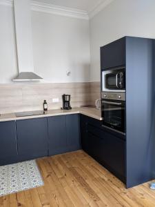a kitchen with blue cabinets and a microwave at Logis de la Grande Rue, appt cœur de ville, spacieux, lumineux, parquet 3 chbres, - 6 pers in La Flèche