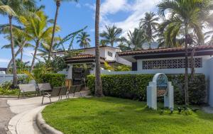 a white house with chairs and palm trees at Casa Isleña in Rincon