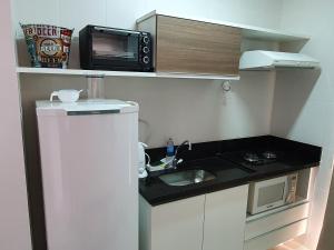 uma pequena cozinha com um micro-ondas e um lavatório em Veredas do Rio Quente - Flat 726 - Fantástico!!! em Rio Quente
