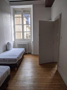 a bedroom with two beds and a window at Logis de la Grande Rue, appt cœur de ville, spacieux, lumineux, parquet 3 chbres, - 6 pers in La Flèche