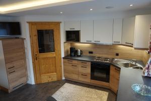 a kitchen with white cabinets and a sink at Komfort Appartements Talbach in Hippach