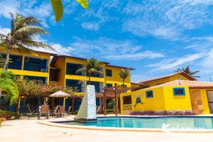 a resort with a swimming pool and a yellow building at Kalamari Beach Hotel in Aquiraz